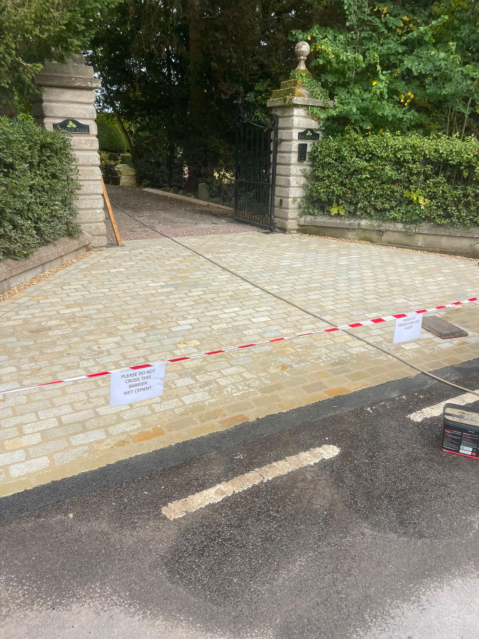 Granite sett driveway entrance apron laid between stone gate pillars and the road — Shropshire