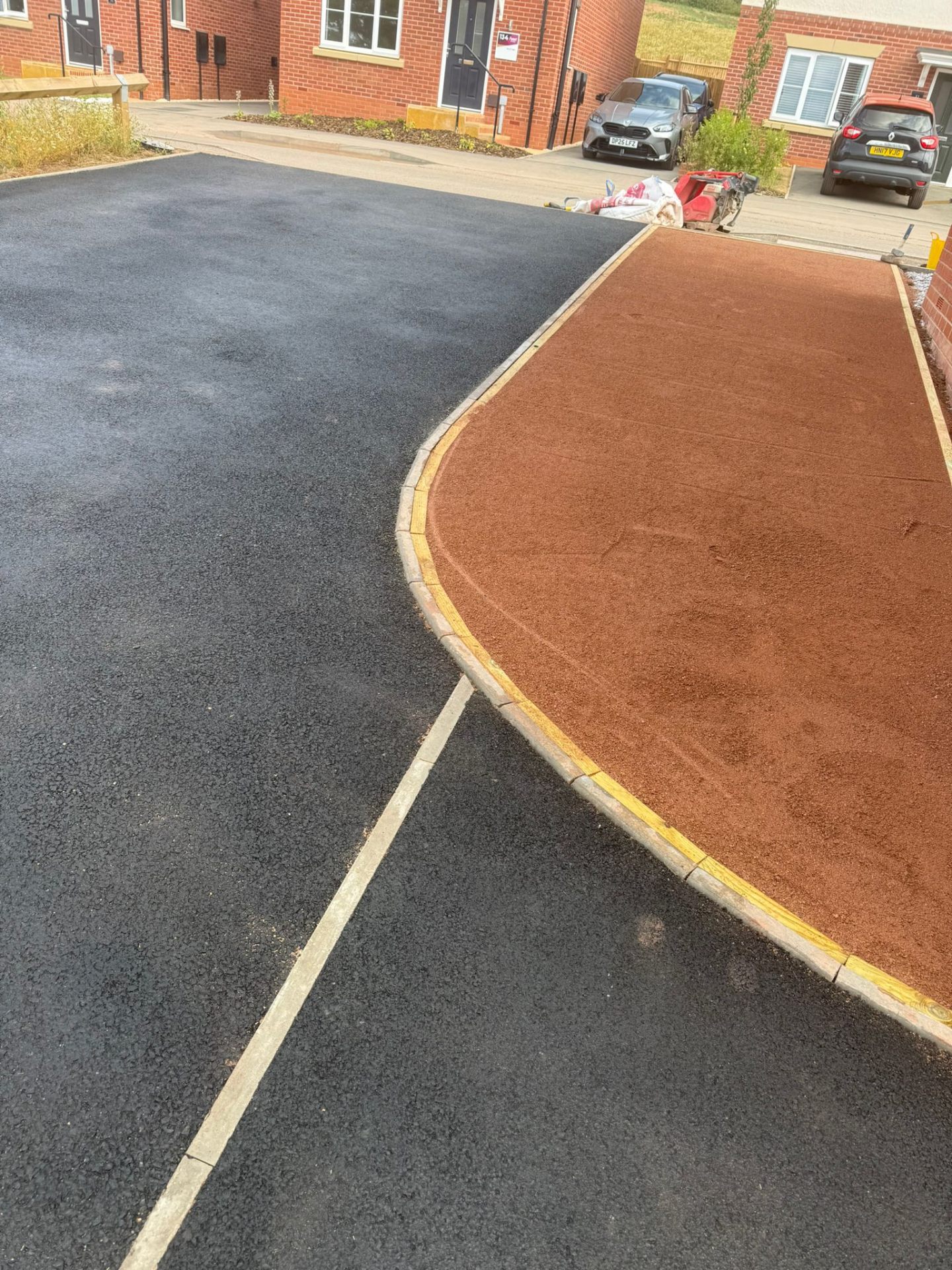 Wide red tarmac base course prepared for resin-bound driveway with kerb detail — Shropshire