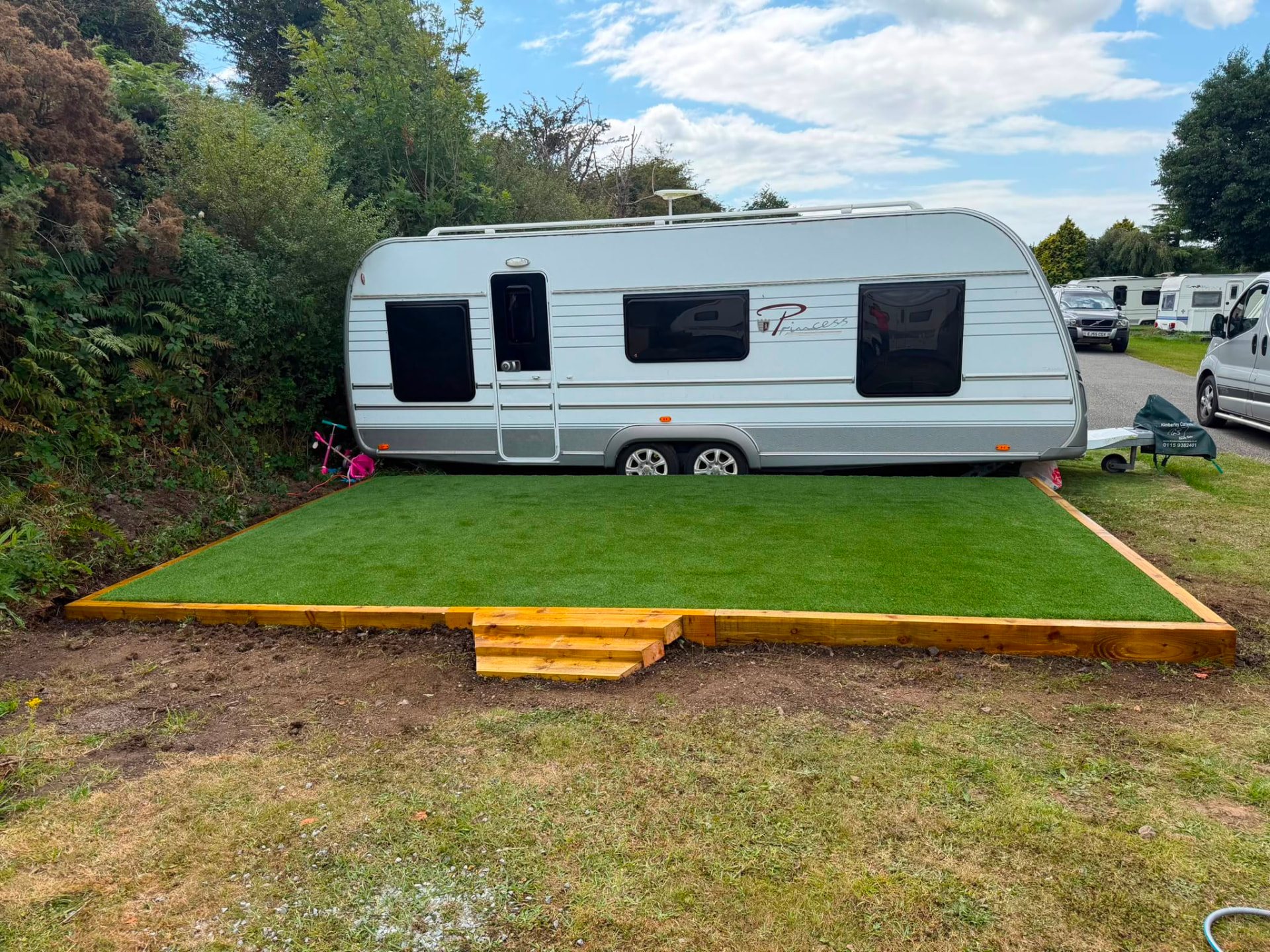 Artificial grass caravan pitch with timber sleeper edging and step — Shropshire
