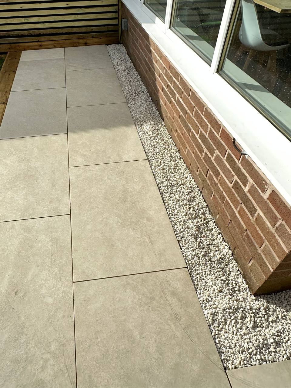 Large format porcelain paving with a white gravel border against the house wall