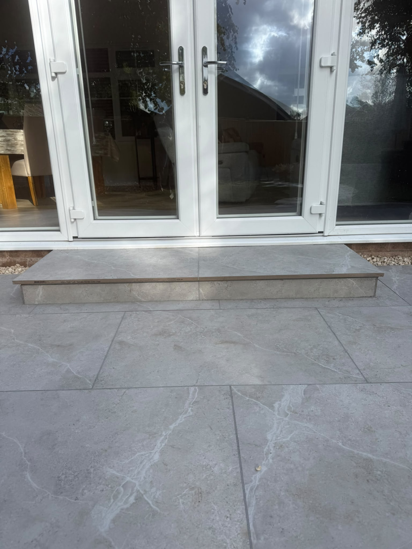Close-up of a grey porcelain patio and bullnose step at French doors