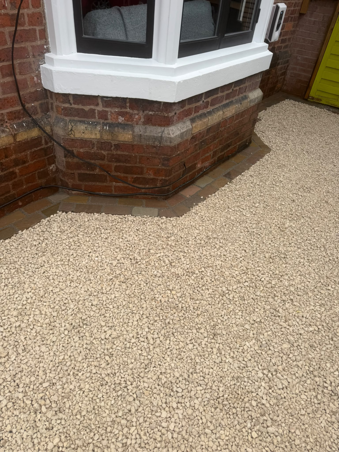 Cream gravel with sandstone sett edging following a Victorian bay window — Shrewsbury